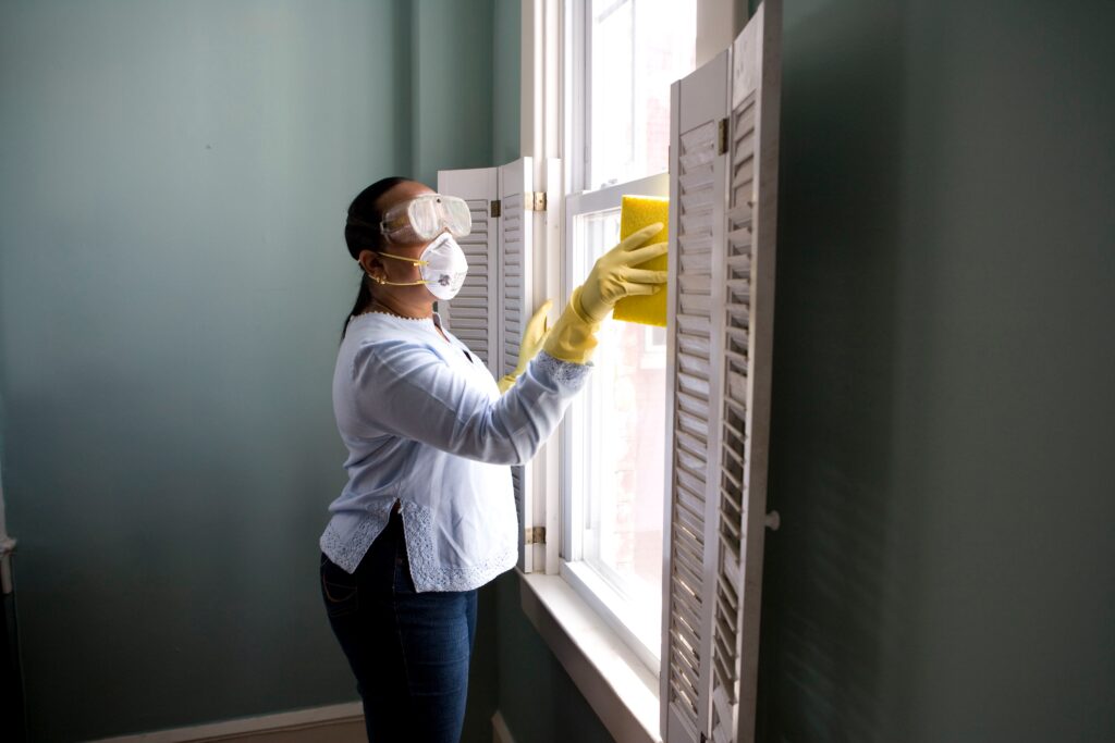lady cleaning window wearing PPE