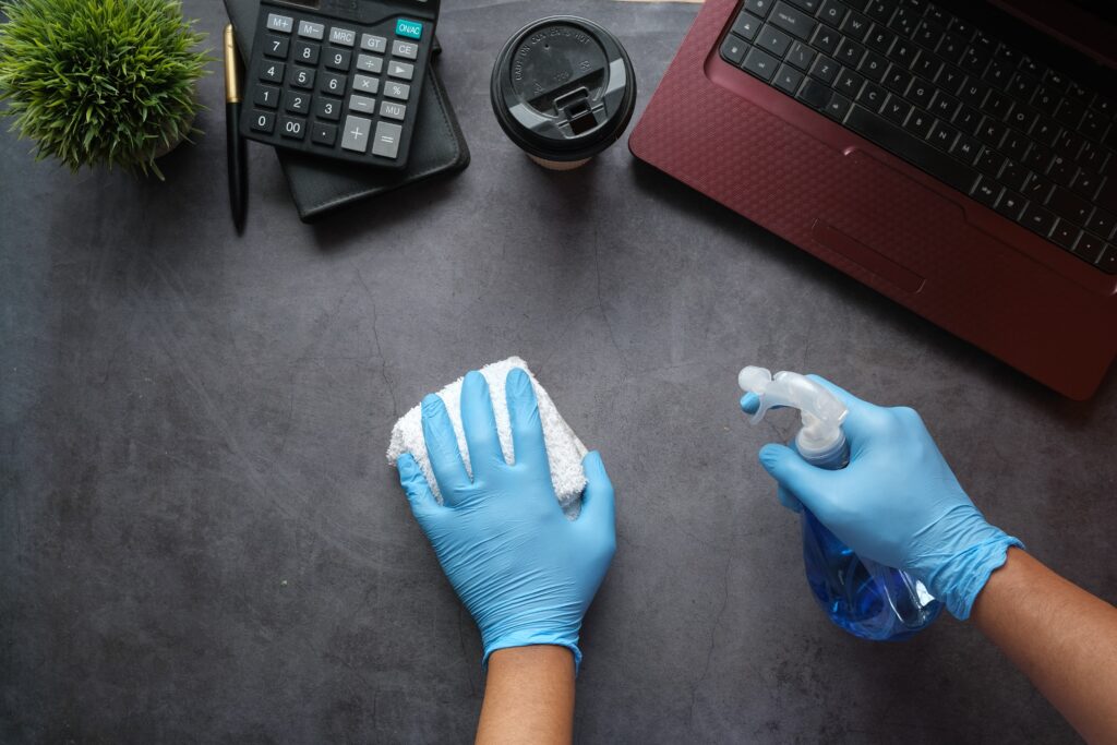 two gloved hands cleaning a desk